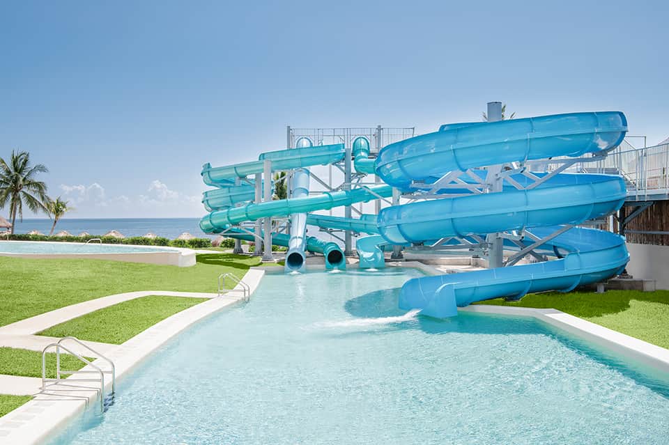 Turquoise water slides and lazy river with manicured lawn and beachfront ocean view