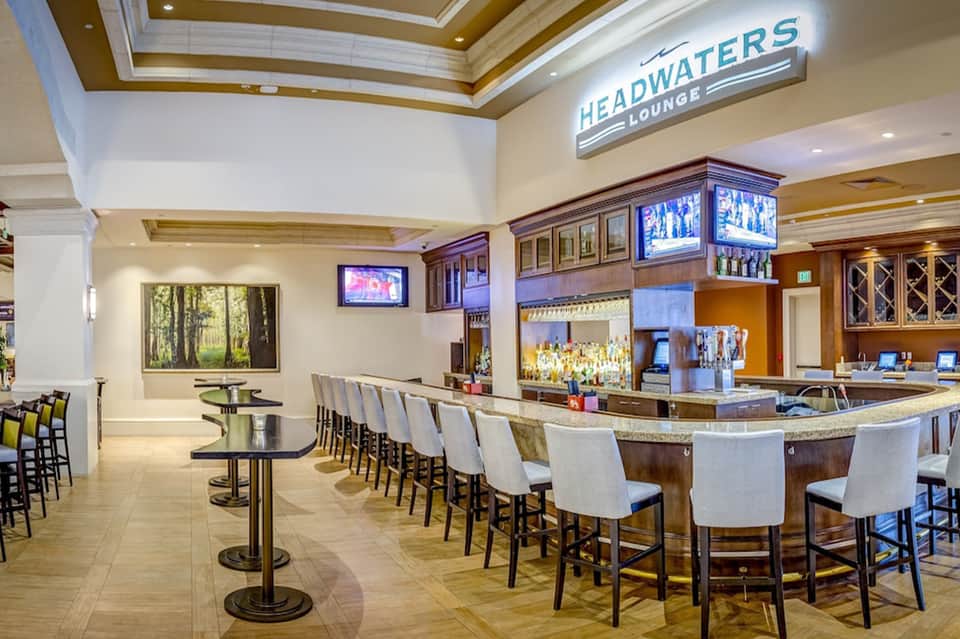 Upscale Headwaters Lounge with high ceiling, bar seating, TVs, and elegant architectural details