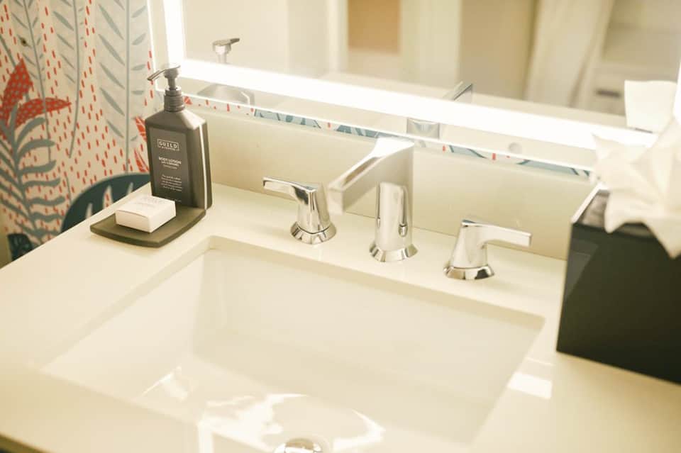Modern bathroom vanity with white sink, chrome faucet, and decorative patterned shower curtain