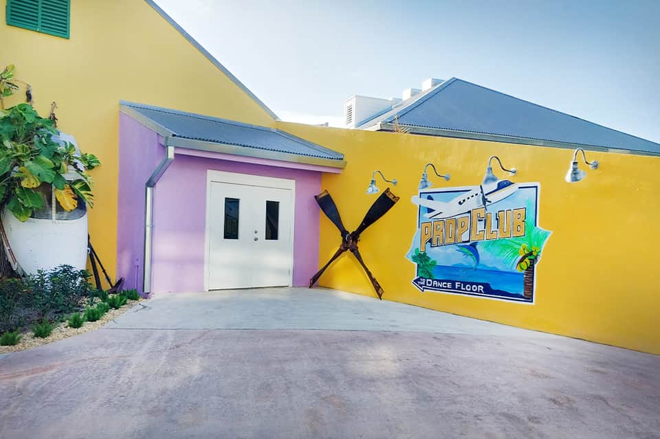 Bright yellow building with pink entrance and propeller club dance floor sign