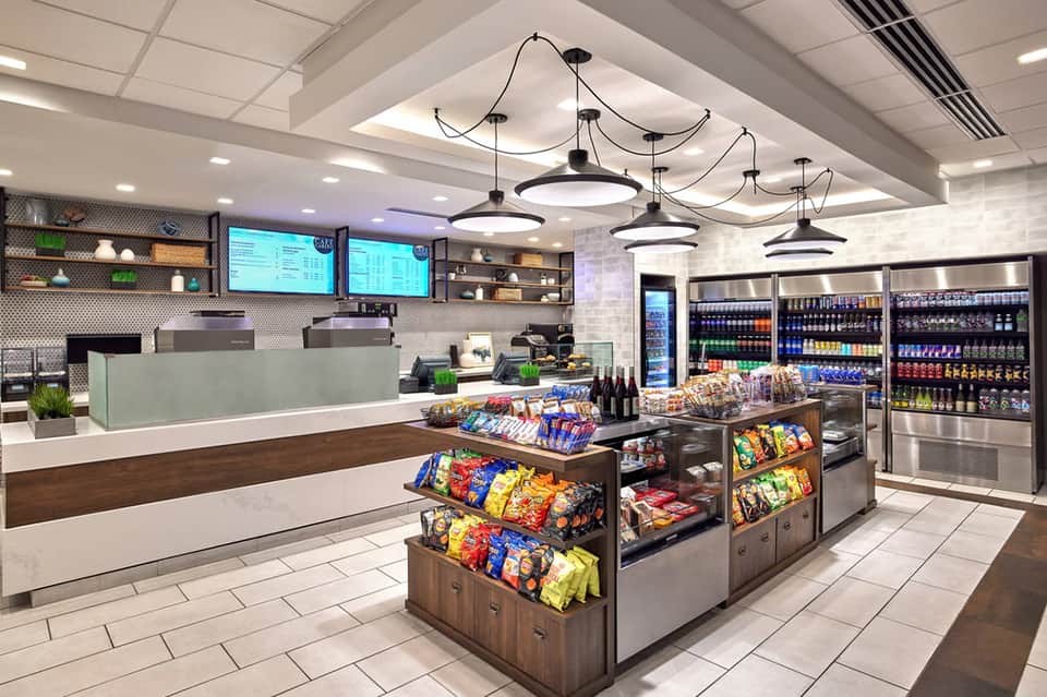 Modern convenience store interior with checkout counter, snack displays, and refrigerated beverage cases