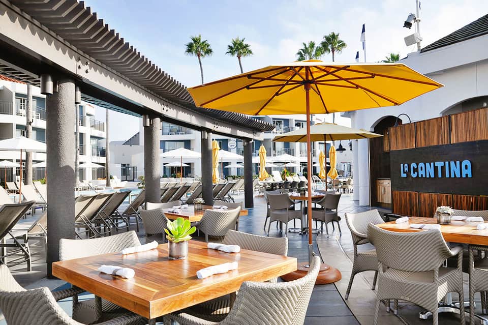La Cantina restaurant patio with yellow umbrellas, wooden tables, and modern seating under covered architecture