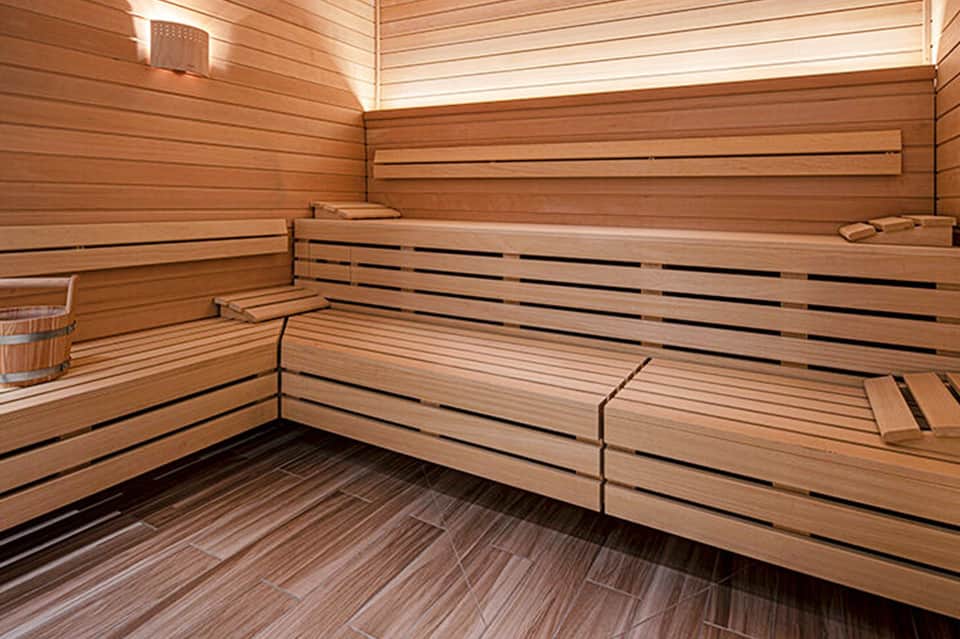 Modern sauna interior with wooden benches, horizontal slats, and soft lighting throughout
