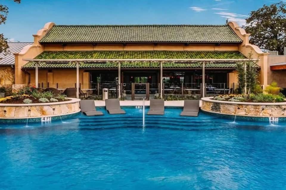 Luxury resort pool with loungers and Asian-inspired architecture featuring green tile roofing