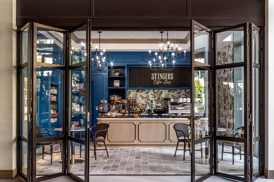 Modern coffee shop interior with blue walls, black framed glass doors, and pendant lighting
