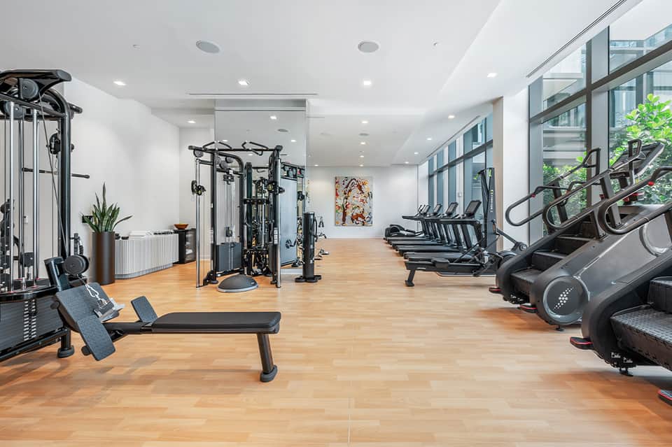 Modern fitness center with cardio equipment, weight machines, and wooden flooring