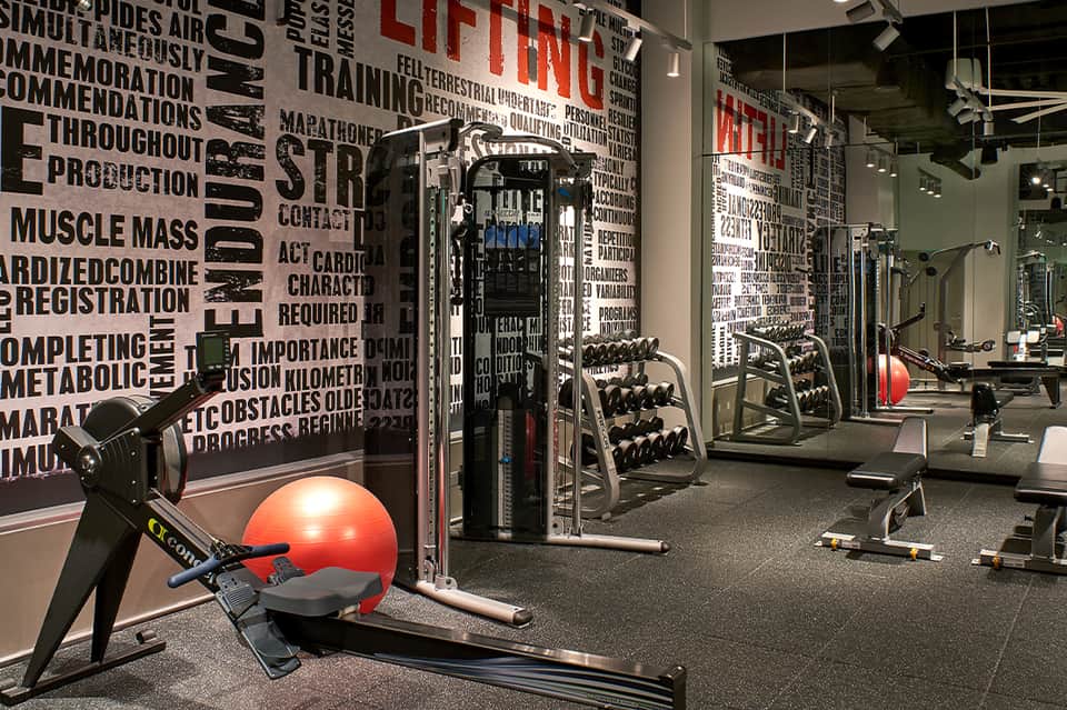Modern fitness center with cardio equipment, weights, cable machines, and motivational wall text