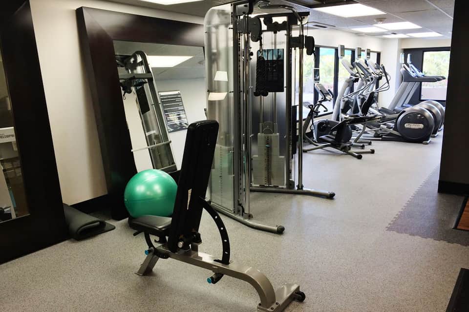 Modern fitness center with cardio equipment, weight machines, and mirrors along the walls