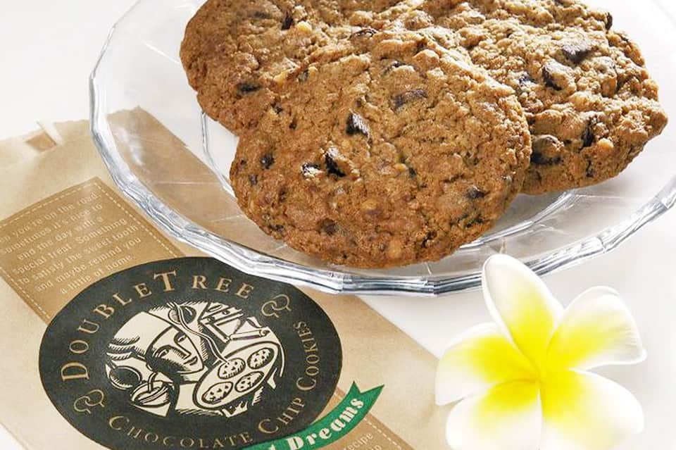 Chocolate chip cookies in clear container with Doubletree hotel branding and yellow flower decoration