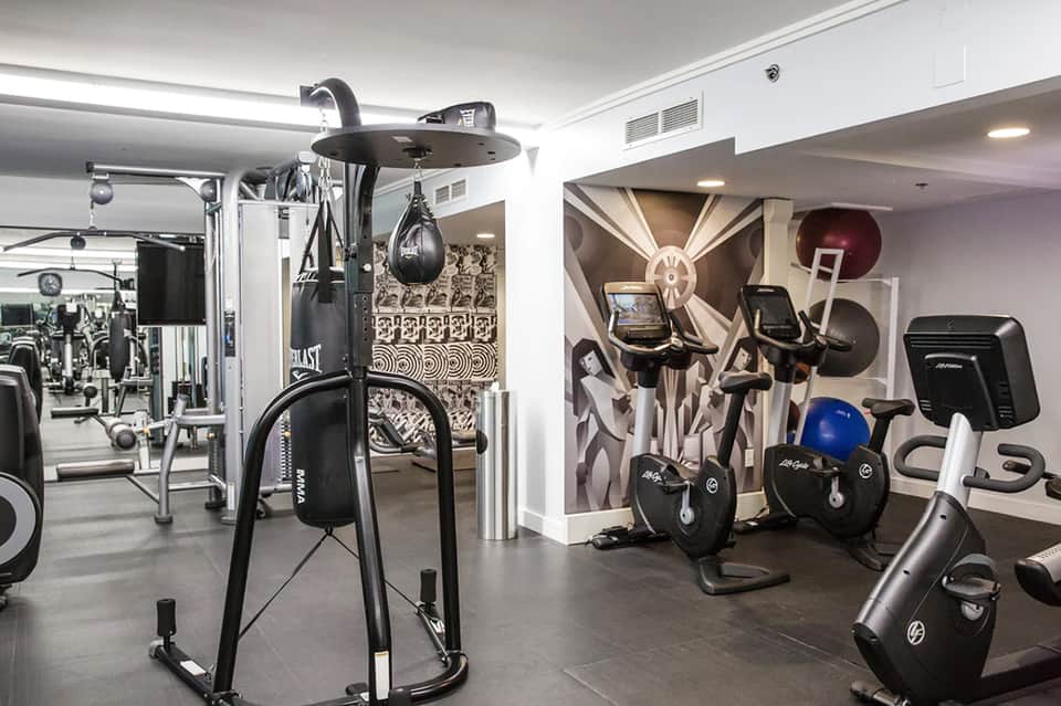 Modern fitness center with cardio equipment, dumbbells, and mirrored walls