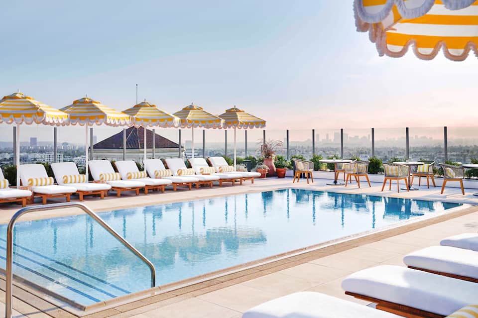 Rooftop pool with yellow and white striped umbrellas overlooking city skyline
