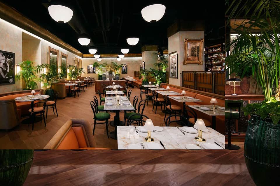 Elegant fine dining restaurant with palm plants, marble tables, and ambient lighting
