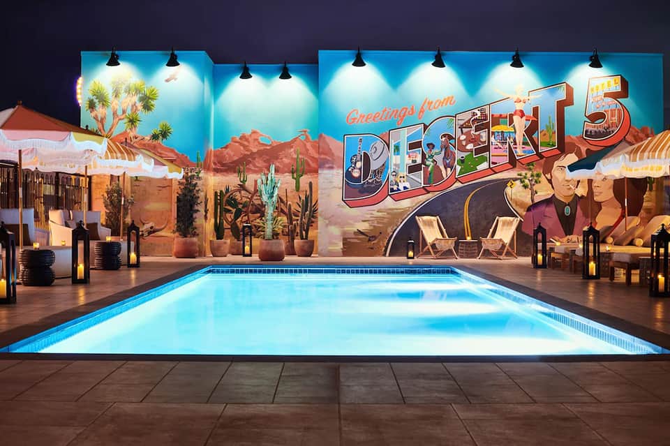 Illuminated Desert 5 pool with vintage neon sign, cacti, and lounge chairs at night