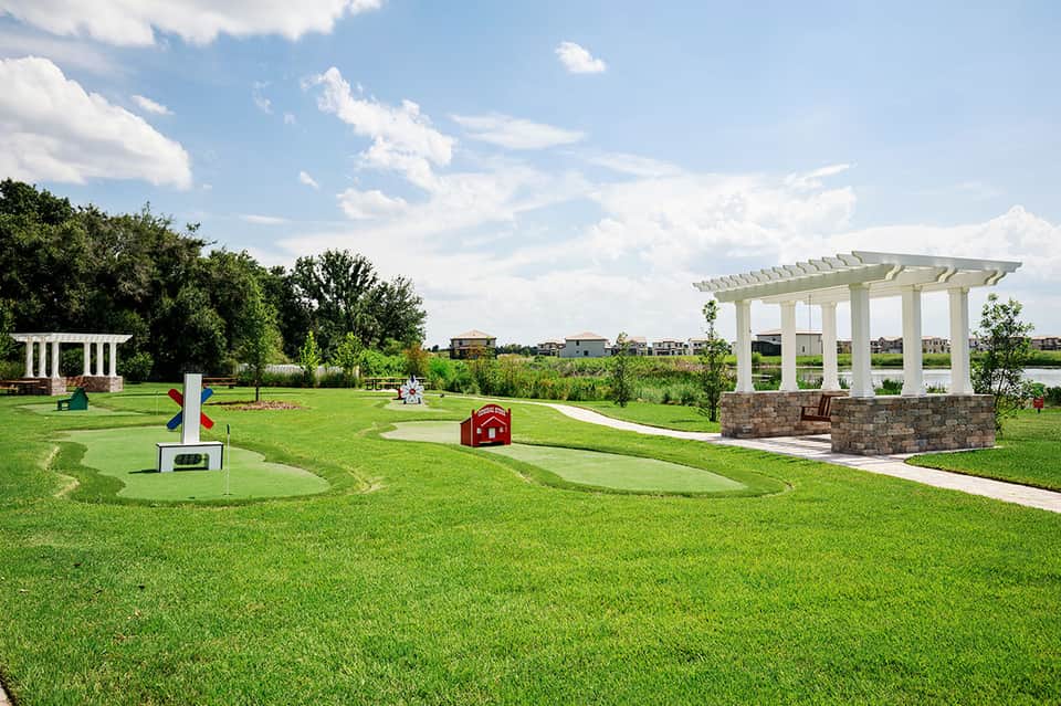 Manicured lawn with white pergolas, gazebo, and play structures at resort community