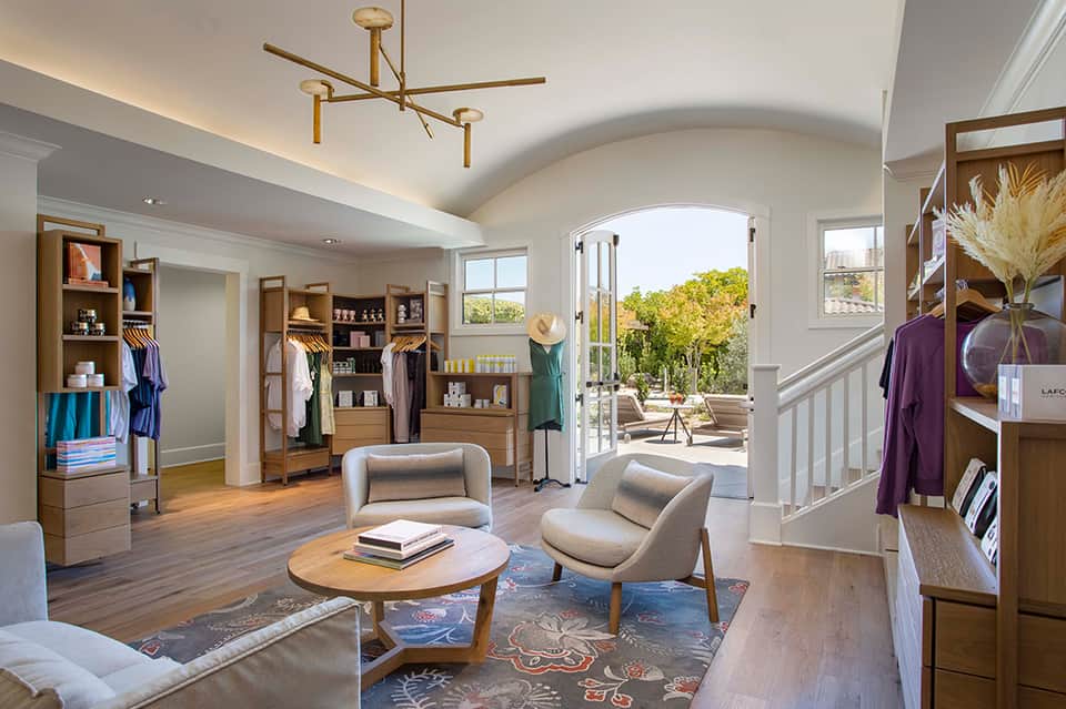 Luxury walk-in closet with wooden shelving, clothing displays, and seating area with arched ceiling