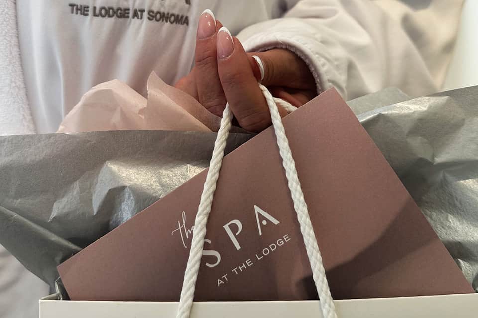 The Lodge at Sonoma spa branded shopping bag with rope handles held by person in white clothing