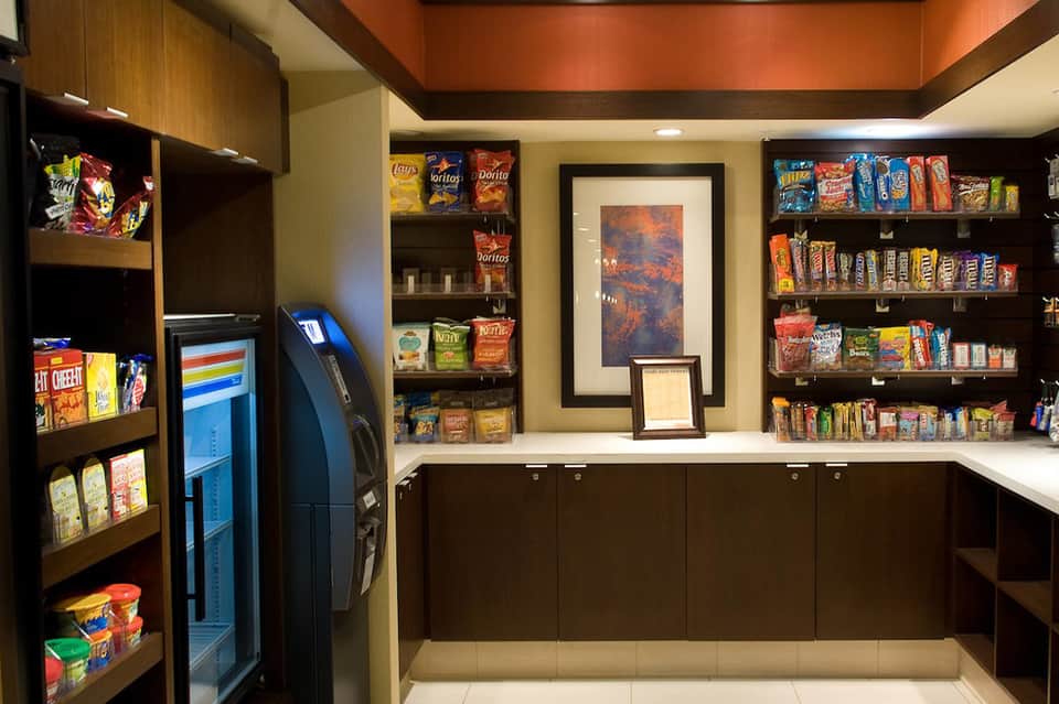 Modern snack shop interior with packaged goods on shelves, vending machine, and checkout counter