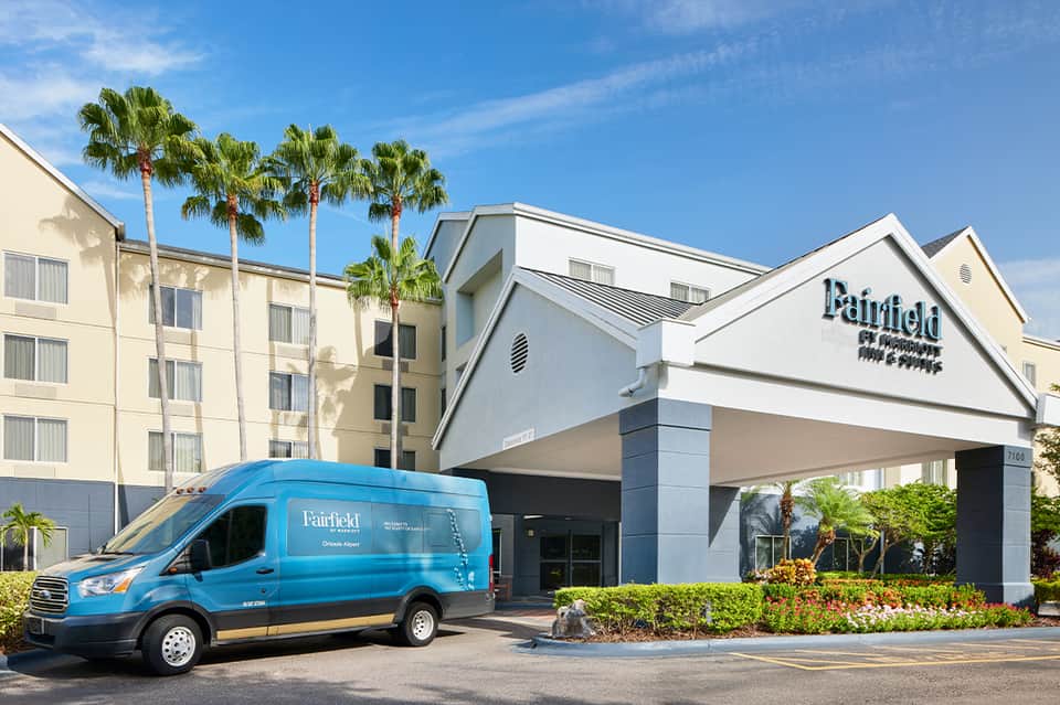 Fairfield by Marriott hotel exterior with blue shuttle van, palm trees, and covered entrance portico