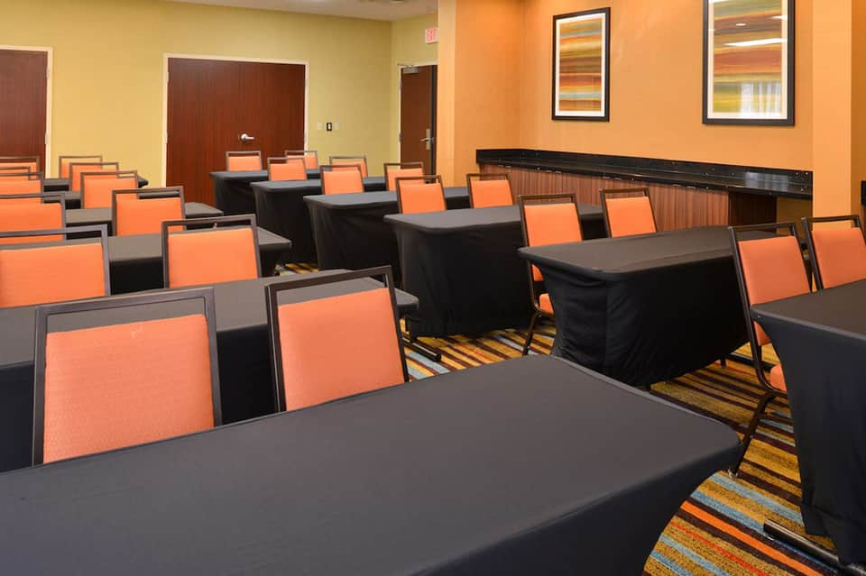 Hotel conference room with black tables, orange chairs, striped carpeting, and yellow-orange walls