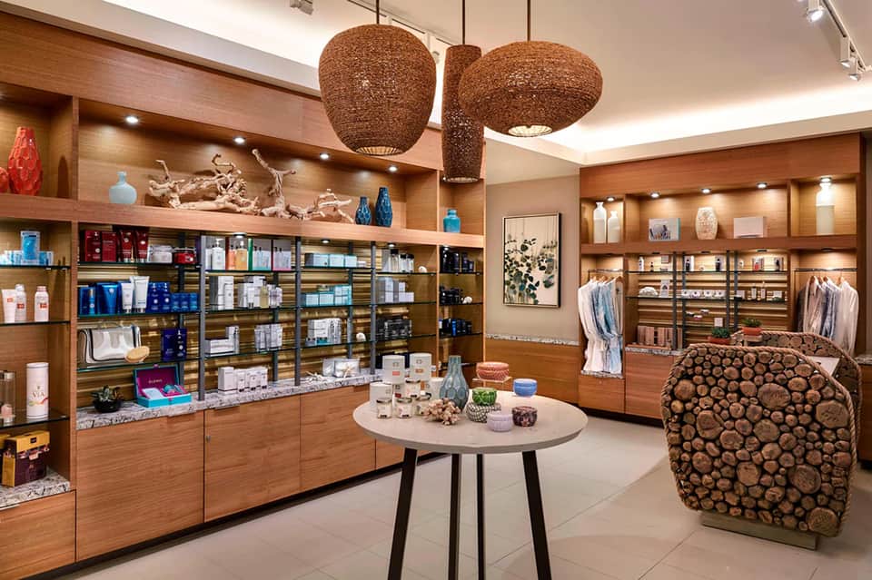 Luxury spa retail store with wooden shelving, woven pendant lights, and product displays