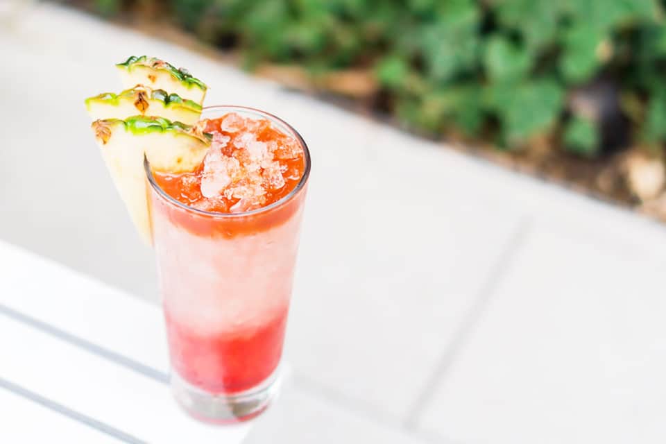 Tropical cocktail with pineapple garnish and crushed ice on outdoor patio