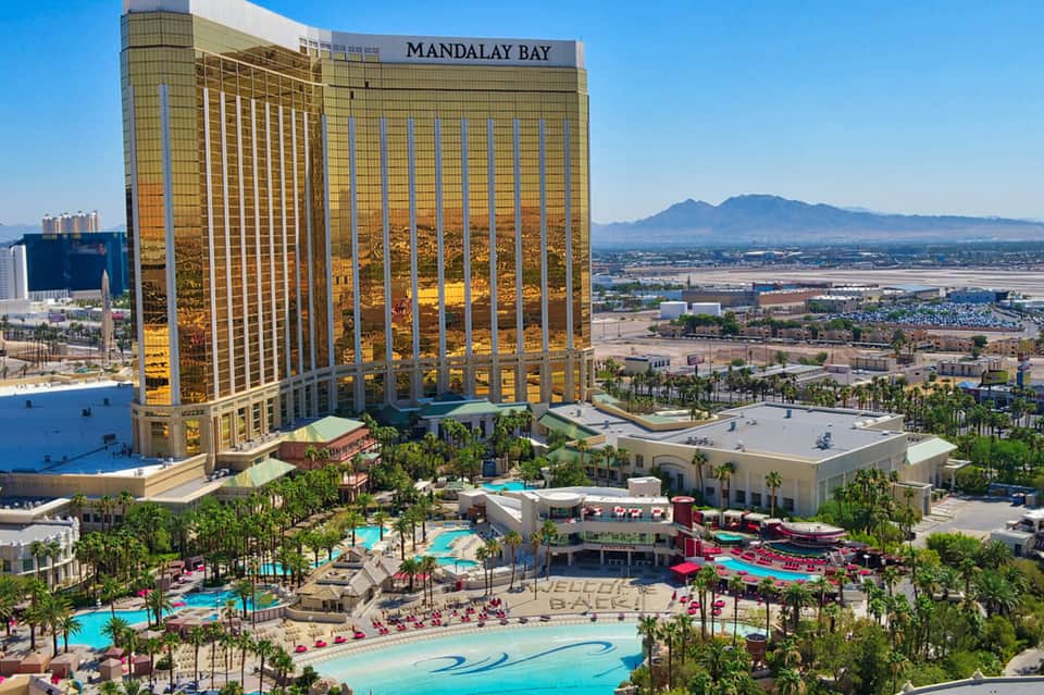 Mandalay Bay hotel tower with golden exterior overlooking Las Vegas valley and pool complex below