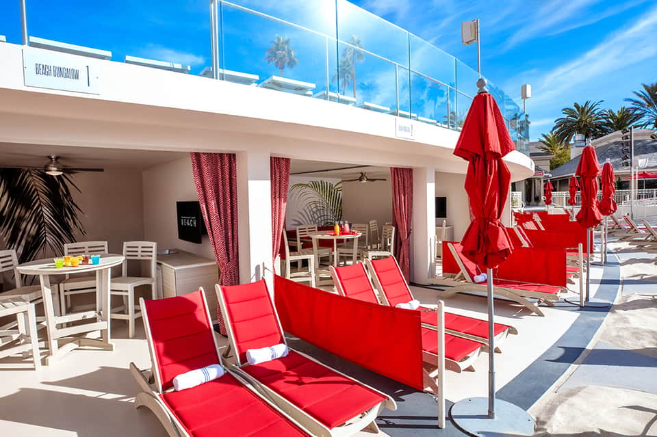 Beachfront bungalow with red umbrellas and lounge chairs overlooking the ocean