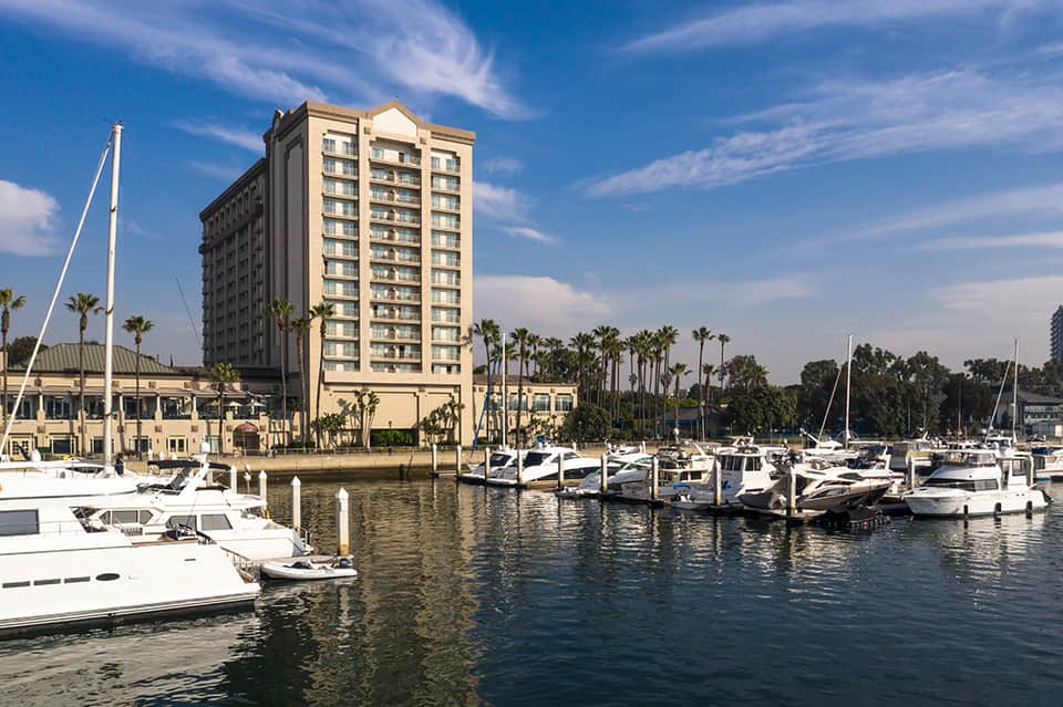 Waterfront hotel with marina docking multiple white boats under clear blue sky