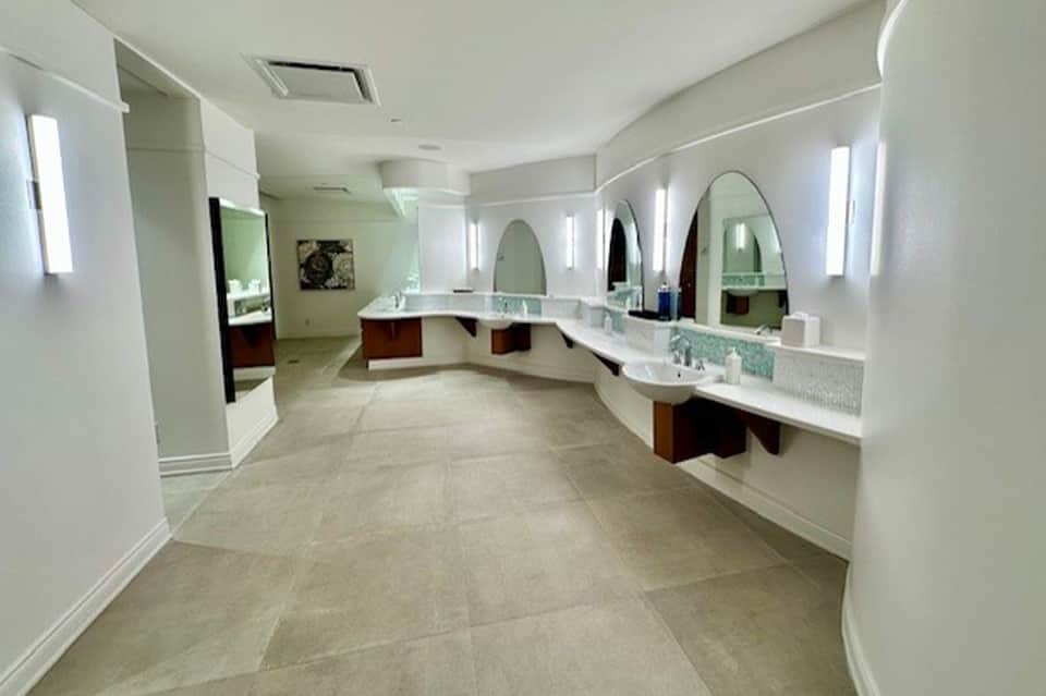 Spacious spa bathroom with multiple vanities, large mirrors, and neutral tile flooring