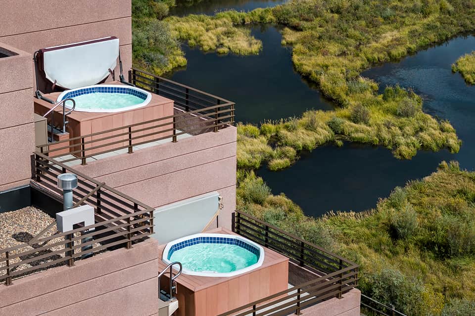 Aerial view of two hot tubs on multi-level deck overlooking wetlands and waterway
