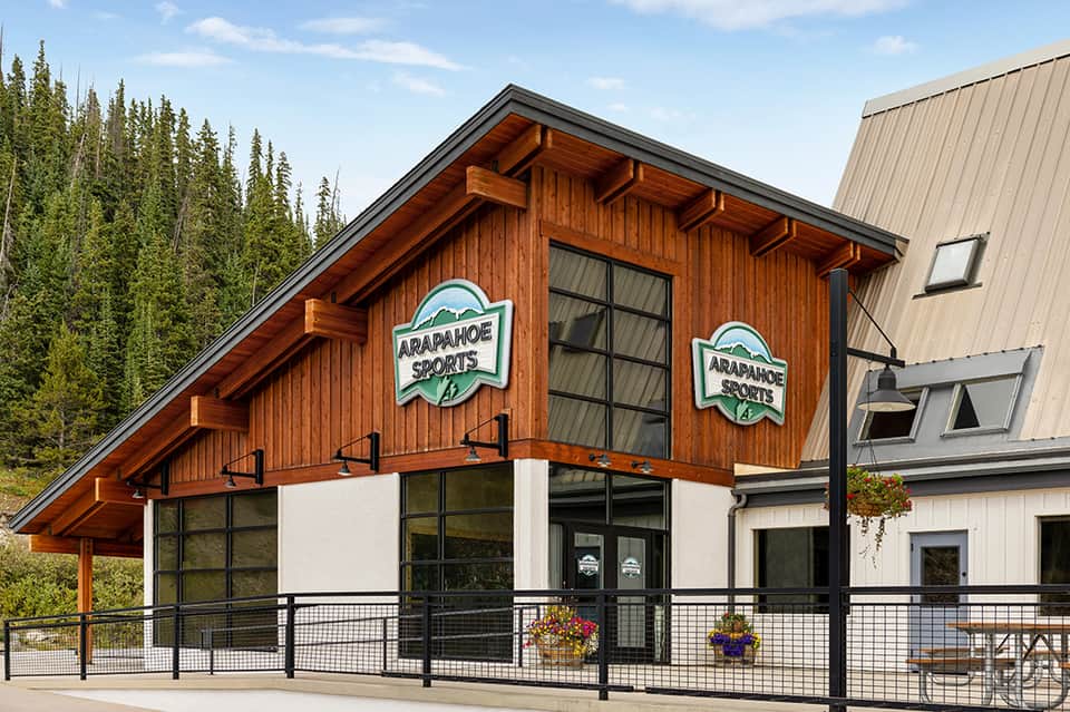 Rustic wooden sports lodge building with large windows and mountain forest backdrop