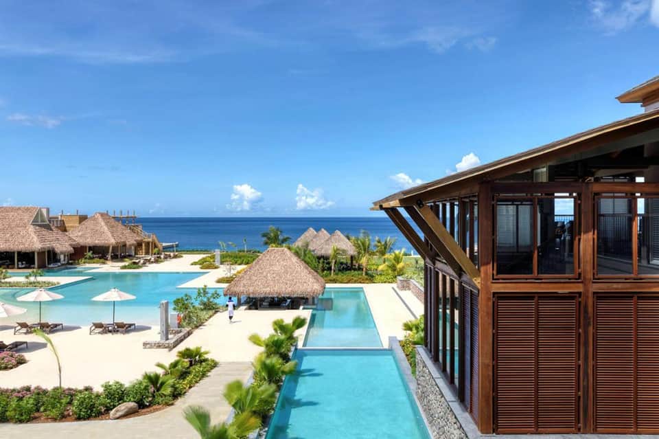 Luxury beach resort with infinity pool, thatched-roof bungalows, and ocean view overlooking turquoise waters