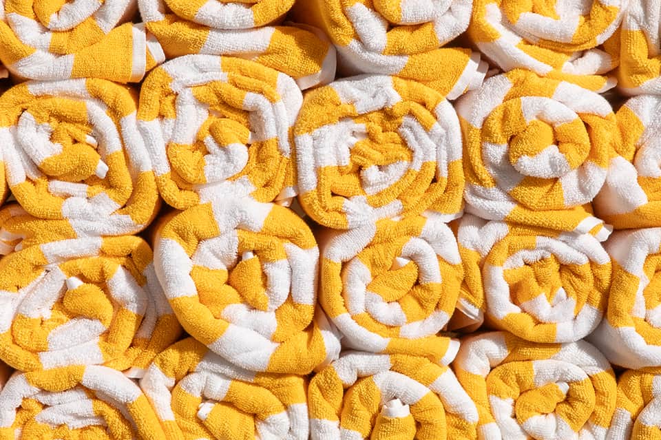 Stack of yellow and white rolled towels displayed closely together