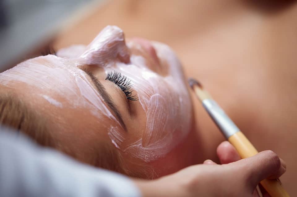 Close-up of face mask application with brush on skin during spa treatment