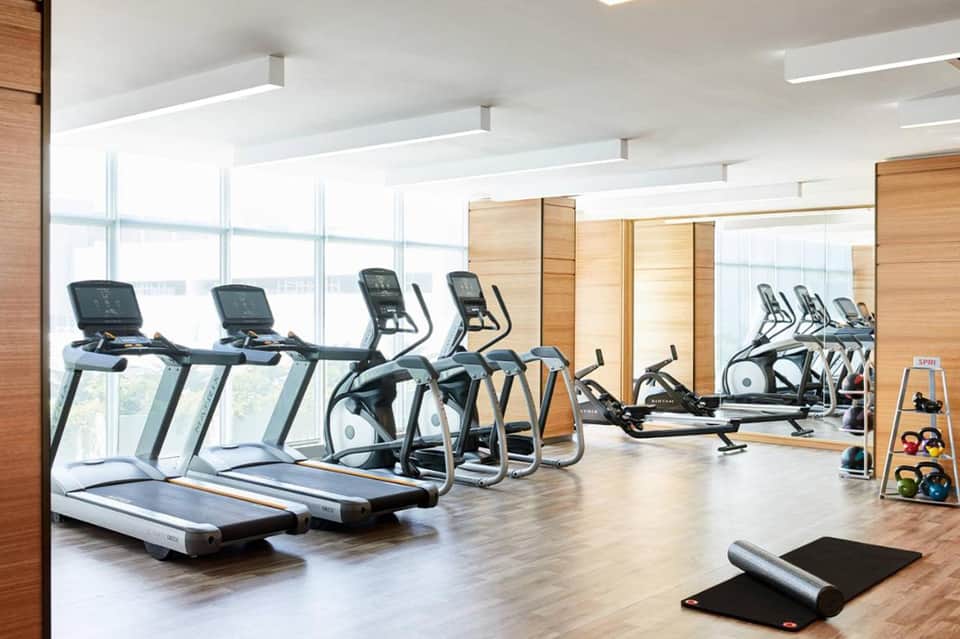 Modern fitness center with treadmills, ellipticals, and exercise equipment facing large windows