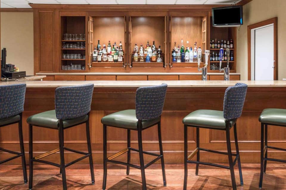 Full-service bar with wood cabinetry displaying multiple liquor bottles and bar seating
