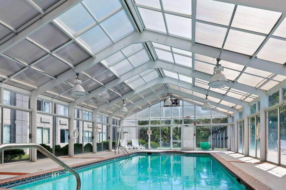 Indoor swimming pool with glass ceiling and natural light in spacious atrium