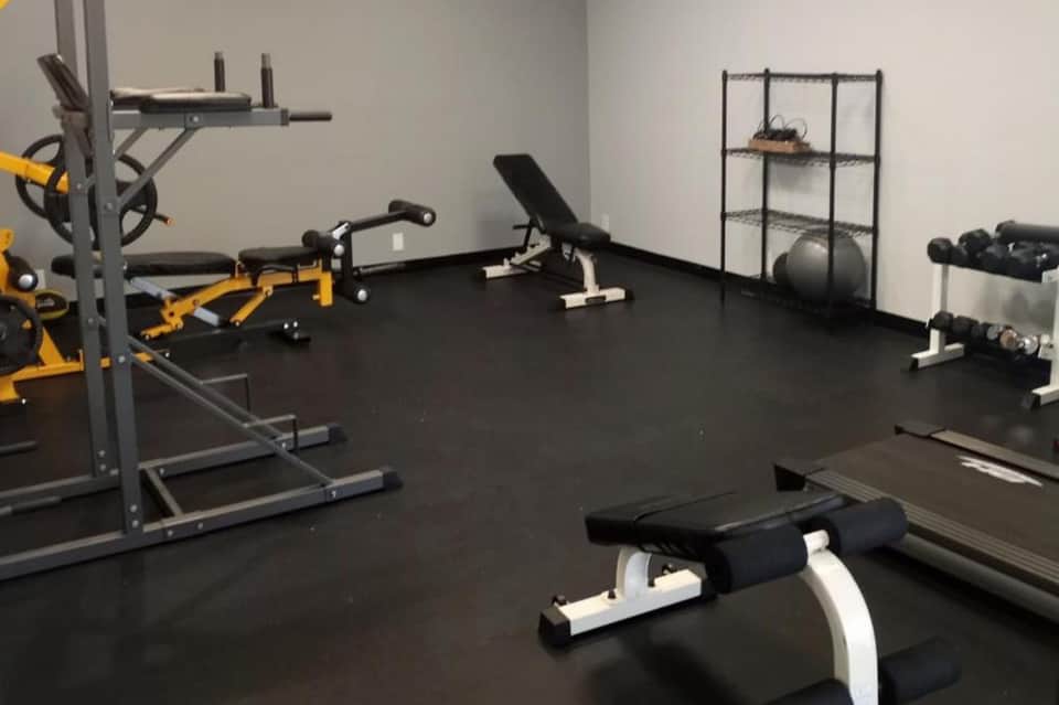 Modern home gym with yellow equipment, dumbbells, exercise bench, and stability ball