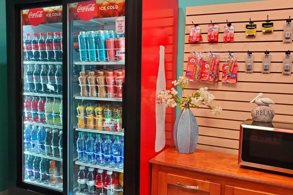 Hotel lobby with Coca-Cola refrigerators, red accent wall, wooden counter, and decorative vase with flowers