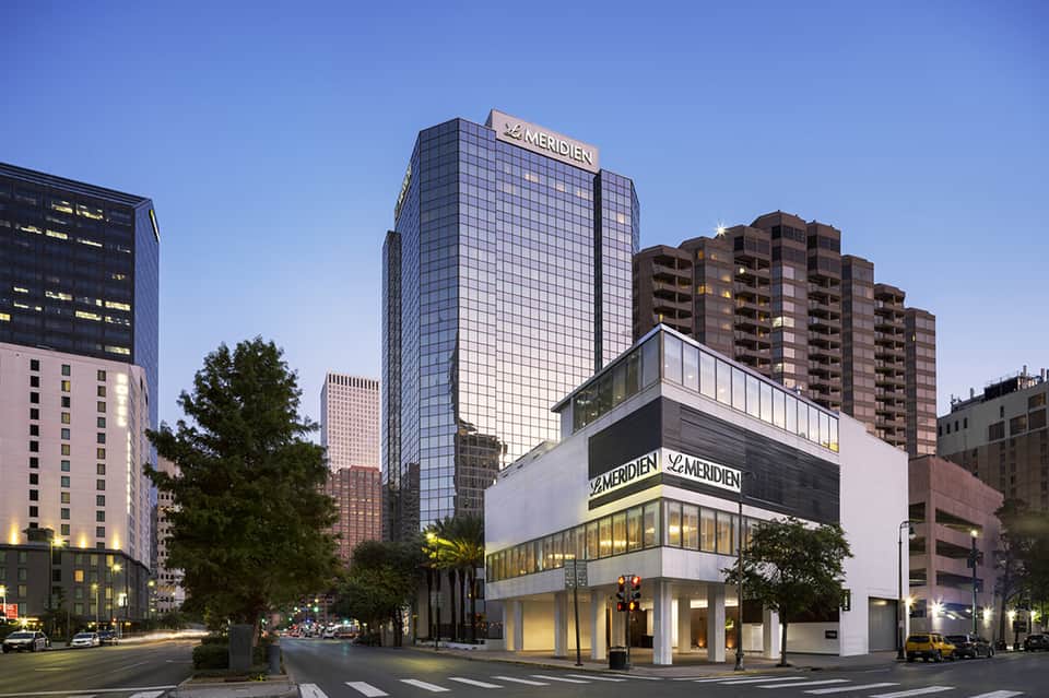 Le Méridien hotel exterior at dusk with modern glass tower and white storefront on urban street