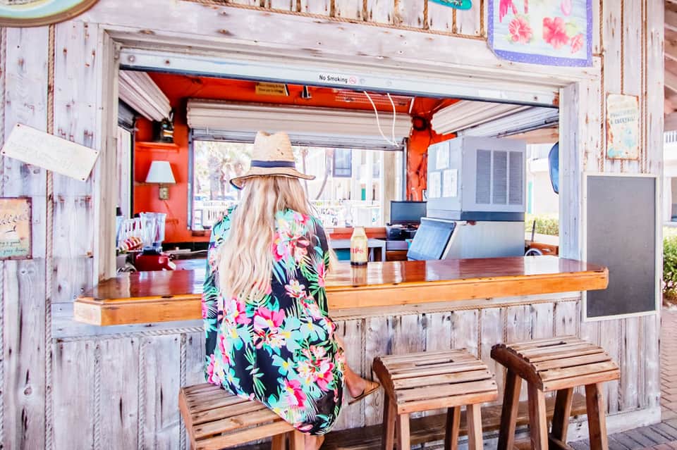 Woman at rustic beachside café counter with weathered wooden interior and red accents