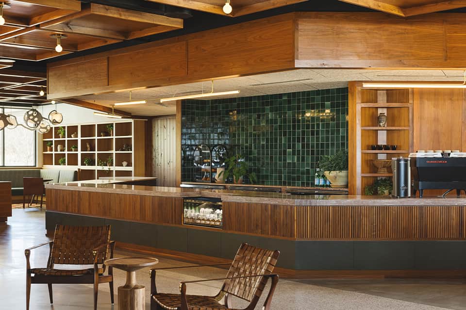 Mid-century modern café with wood paneling, green tile wall, geometric shelving, and contemporary furniture