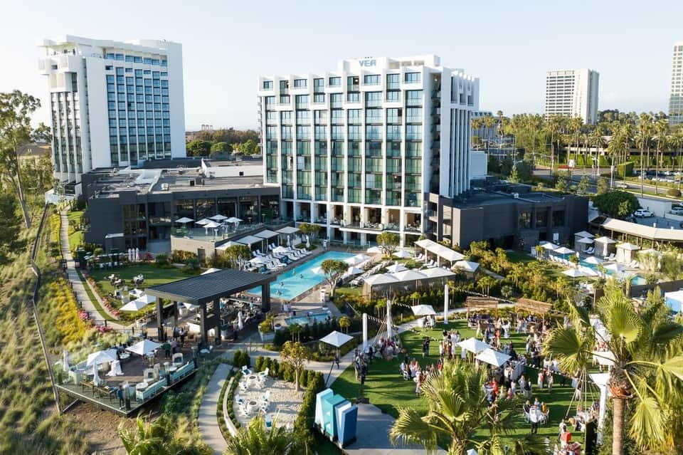 Modern hotel resort with pool, green spaces, and contemporary architecture surrounded by palm trees