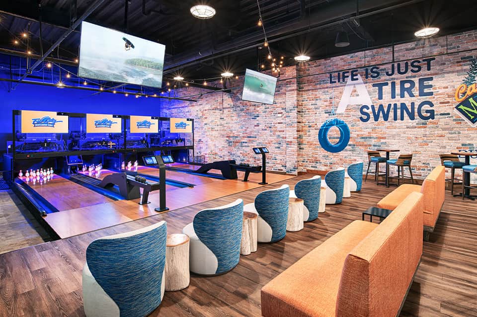 Modern bowling alley with blue lighting, comfortable seating, and motivational wall signage in hotel recreation area