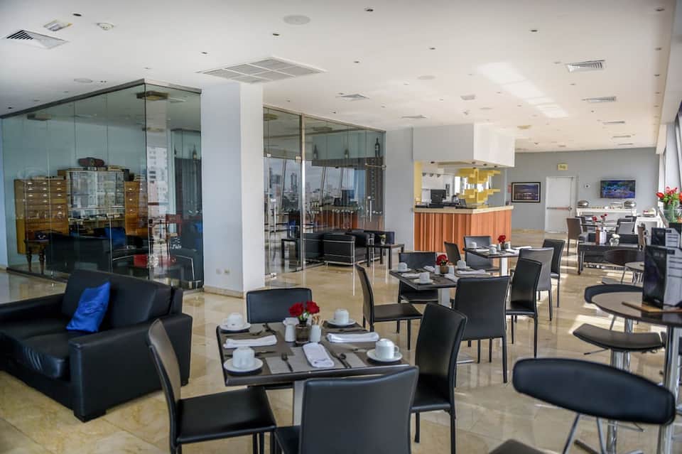 Modern hotel lounge with black furniture, glass partitions, and orange accent details