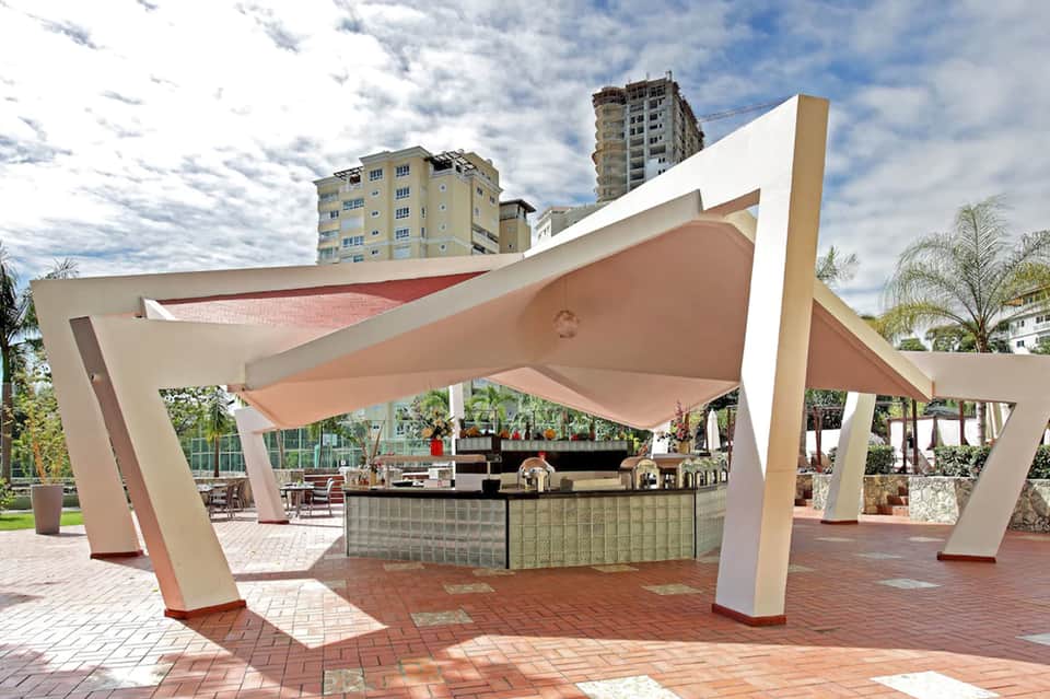 Modern outdoor pavilion with curved white architectural elements and brick patio near waterfront