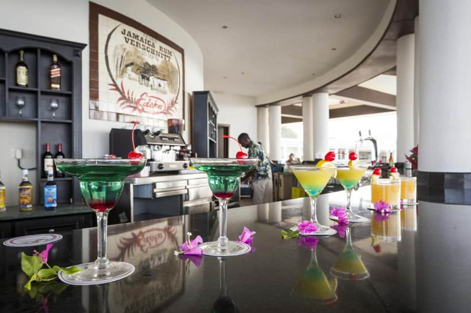 Colorful tropical cocktails with floral garnishes on a black bar counter in an upscale lounge