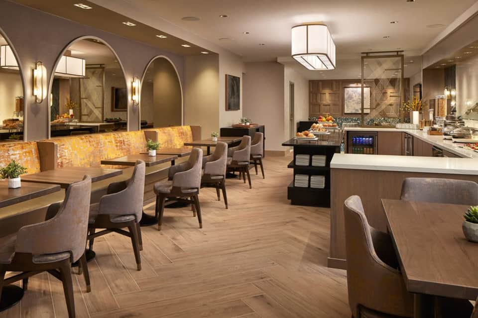 Elegant dining area with booth seating, arched mirrors, wood flooring, and modern lighting fixtures