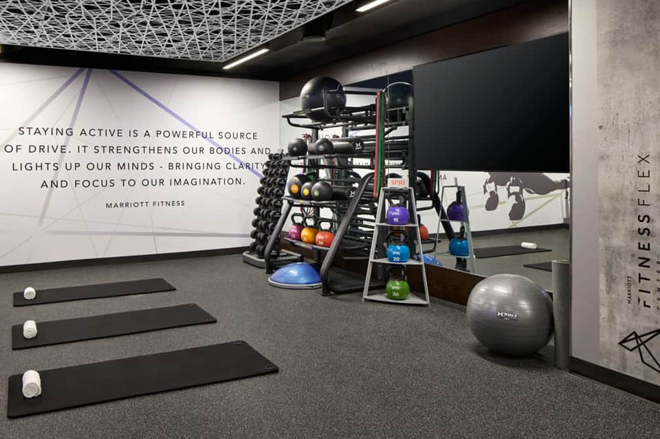 Modern fitness center with dumbbells, kettlebells, exercise mats, and motivational signage