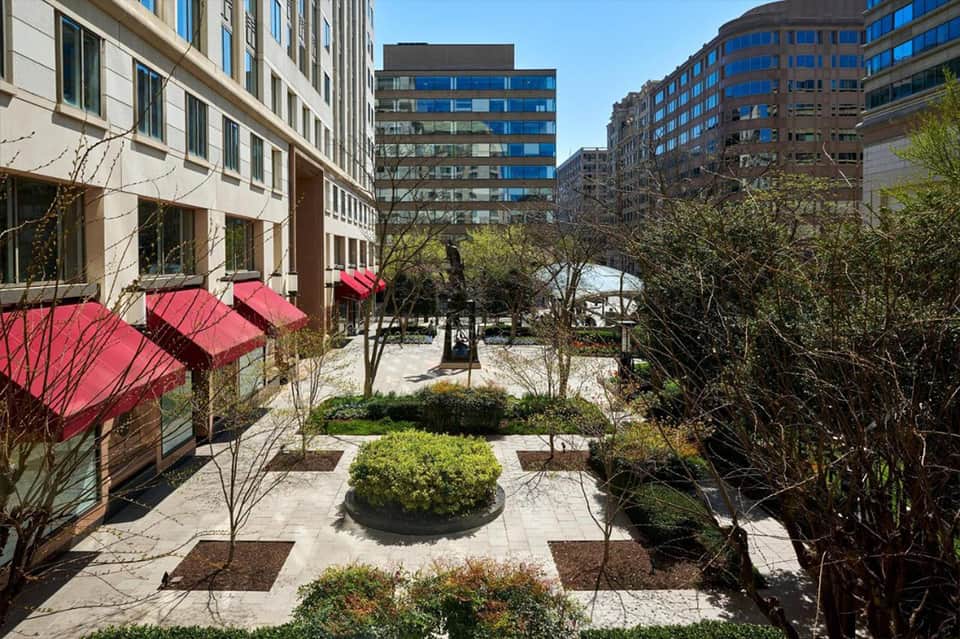 Urban courtyard with pink umbrellas, landscaped gardens, and modern apartment buildings surrounding